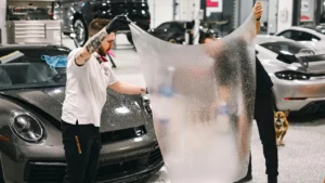 Two detailing professionals applying paint protection film on a car