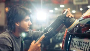A man runs a polisher on a black coloured car inside a detailing bay
