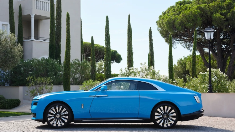 A blue Rolls-Royce Spectre parked in the lawn of a mansion