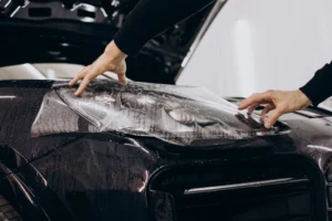 A professional inspecting the flawless factory finish of a car after removing the paint protection film.