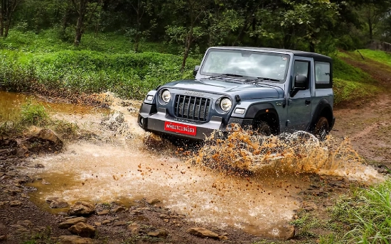 A Mahindra Thar driving through a flowing river