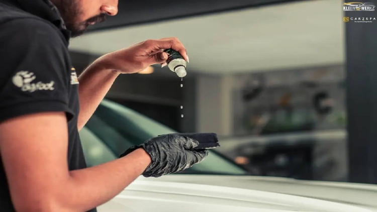 A worker prepares to apply ceramic coating on a white car