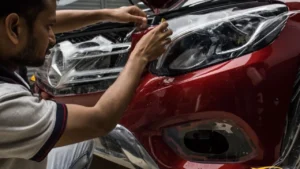 A professional car detailing studio in India with a technician applying coating to a car