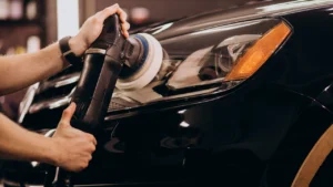 A worker polishing a car inside a car detailing studio