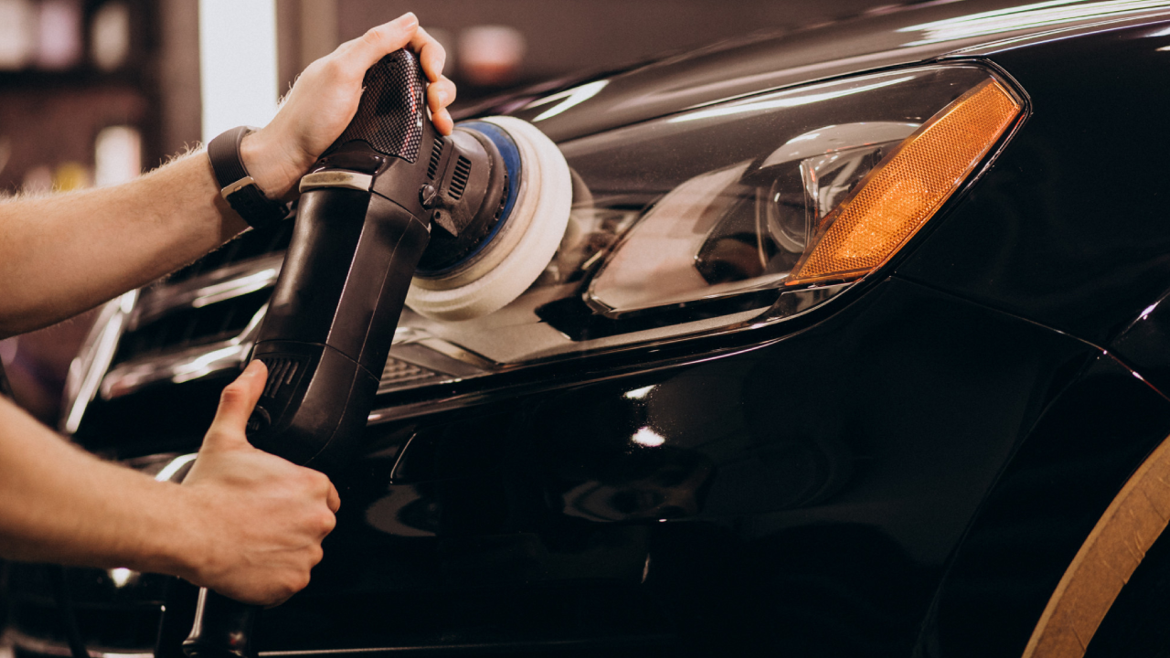 A worker polishing a car inside a car detailing studio