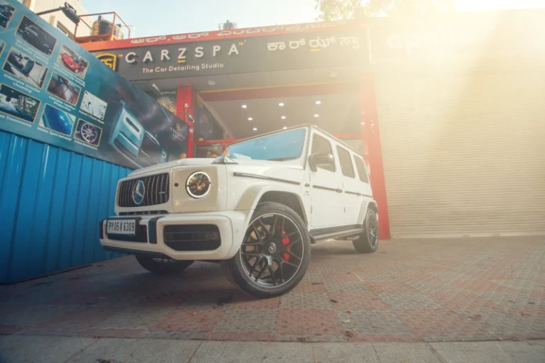 White Mercedes-Benz G-Class SUV parked outside CarzSpa’s detailing studio in bright sunlight.