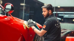 Worker polishes a luxury car inside a detailing studio