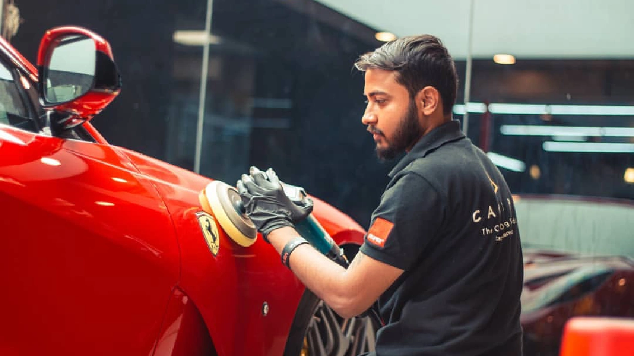Worker polishes a luxury car inside a detailing studio