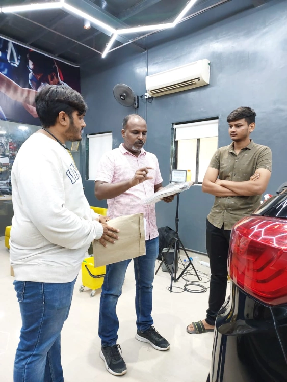 Three men discussing detailing equipment inside a car detailing studio