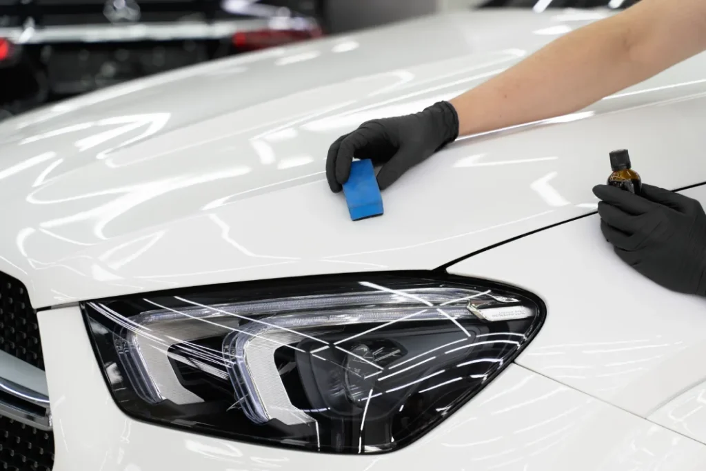A worker applies ceramic coating on a white car
