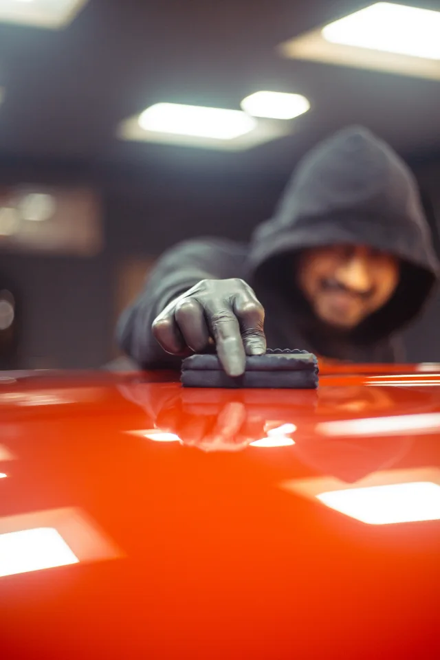 a worker applies ceramic coating on a car