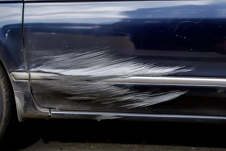 a dark blue car panel with long gashes or scratches