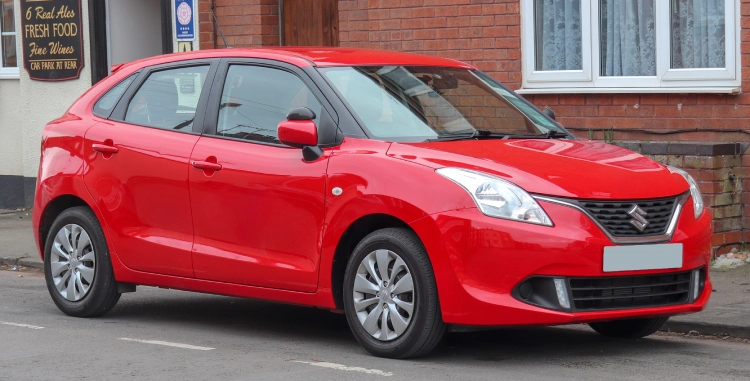 A red Maruti Suzuki Baleno parked on the kerbside