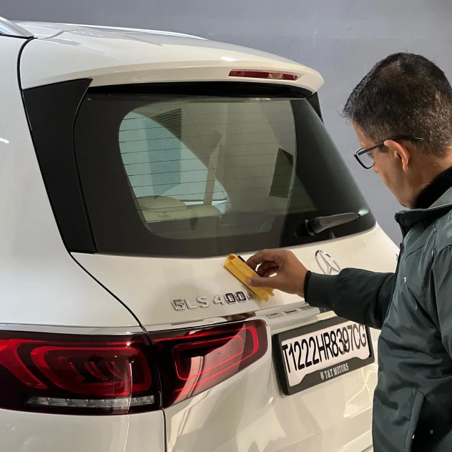 A man applies ceramic coating on the back of the white Mercedes SUV in Gurgaon