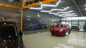 The interior of a car detailing studio with a red-coloured hatchback parked inside