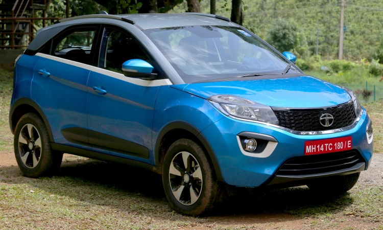A bright blue Tata Nexon parked on an empty plot