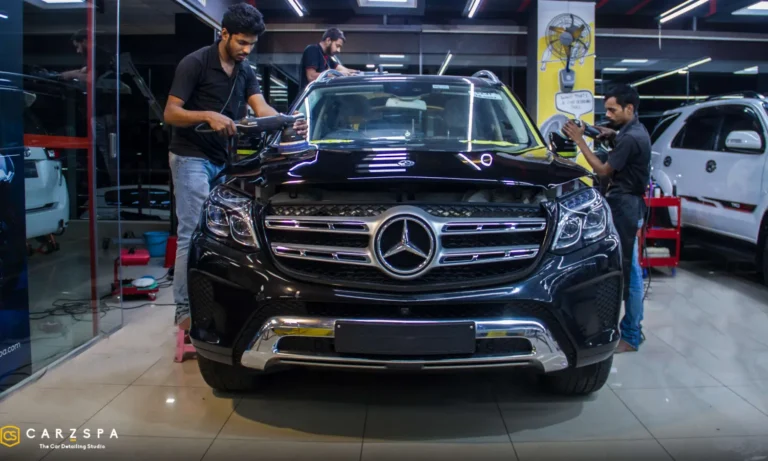 Workers detailing a black Mercedes SUV