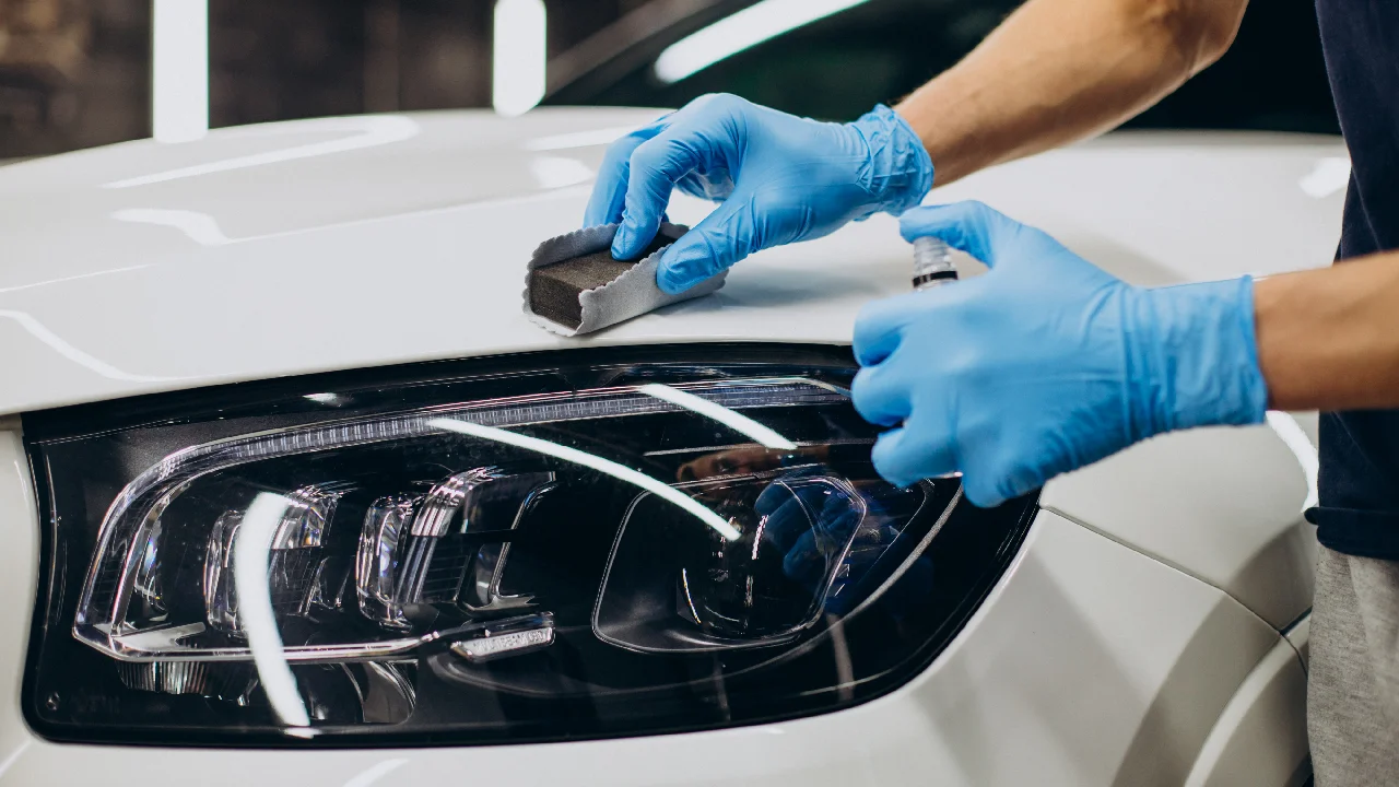 Close-up of a professional detailing technician applying ceramic coating to a car's paintwork