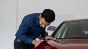 An Indian man joyfully checks out the shiny paint job of his car